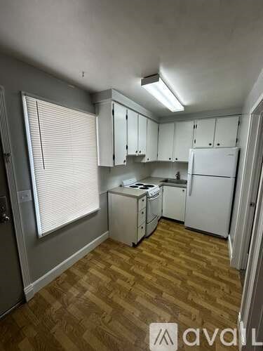 A kitchen with white appliances and wooden flooring.