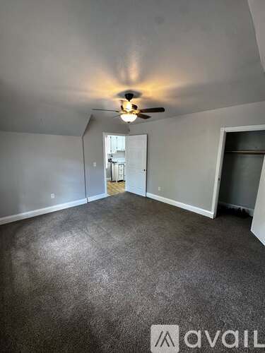 A room with a ceiling fan and carpeted floor.