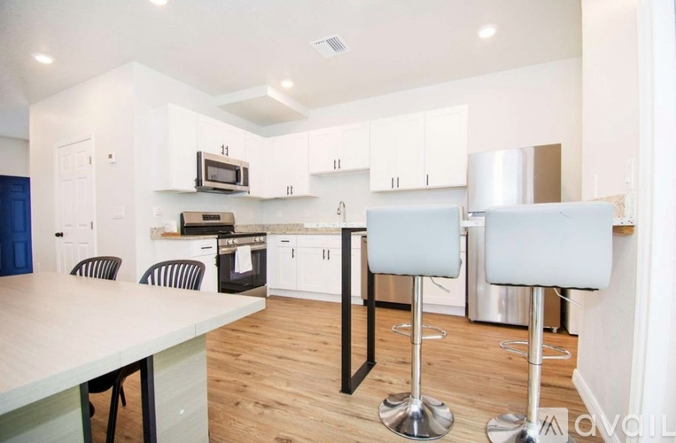 A kitchen with white cabinets and a wooden floor.