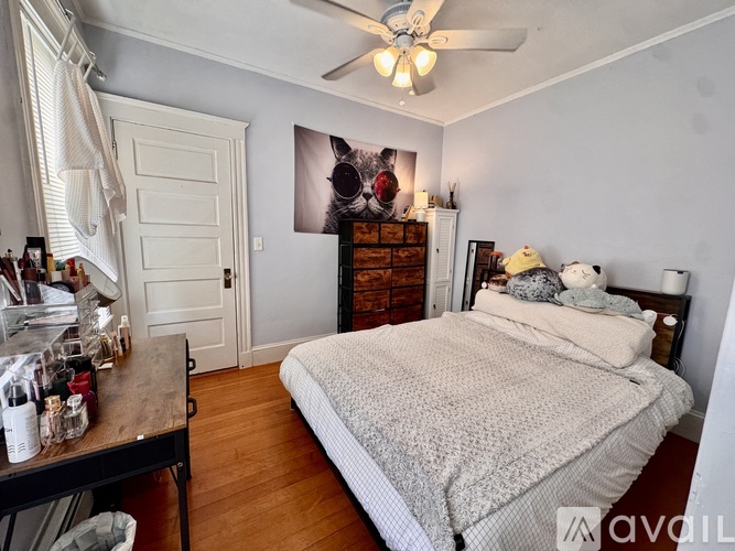 A bedroom with a bed, dresser, and a ceiling fan.