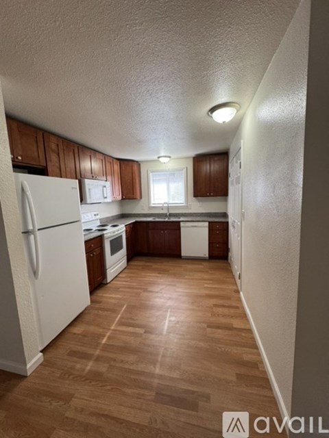 A kitchen with wooden floors and white appliances.