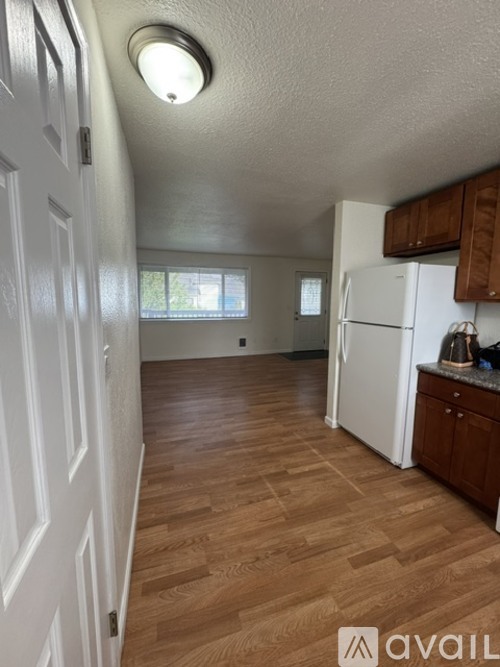 A kitchen with a white fridge and wooden floors.