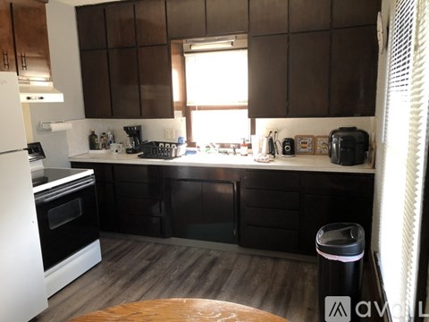 A kitchen with dark brown cabinets and a white fridge.