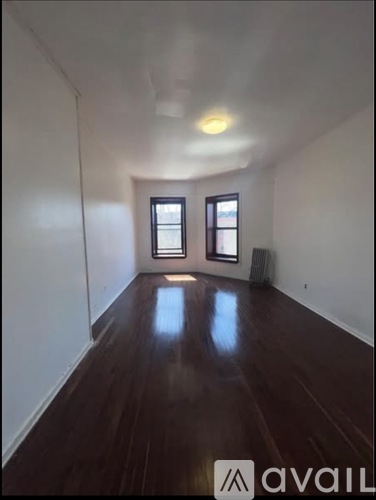 A room with wooden floors and two windows.