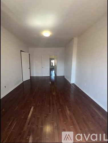 A hallway with wood flooring and white walls.