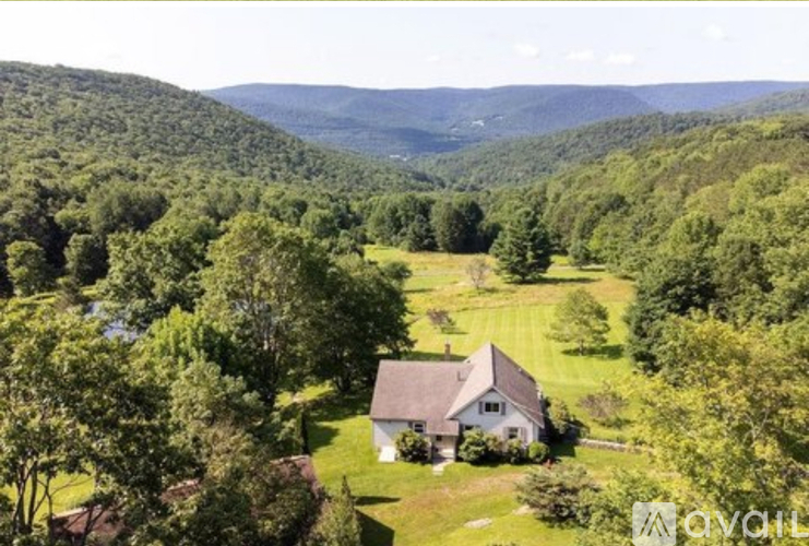 A house is surrounded by trees in a lush green landscape.