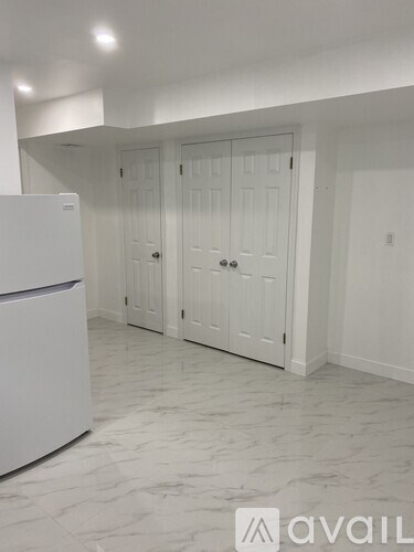 A kitchen with a white fridge and white cabinets.