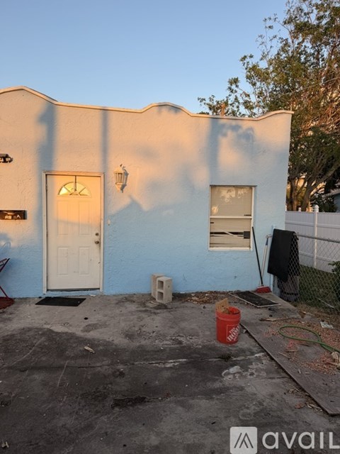 A white door with a window above it and a red bucket on the ground.