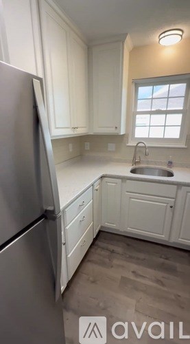A kitchen with white cabinets and a stainless steel refrigerator.
