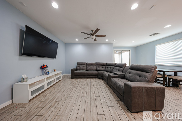 A spacious living room with a large couch and a television mounted on the wall.