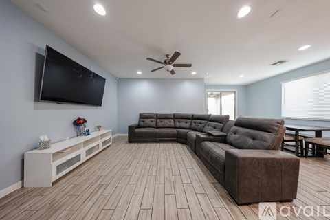 A spacious living room with a large couch and a television mounted on the wall.