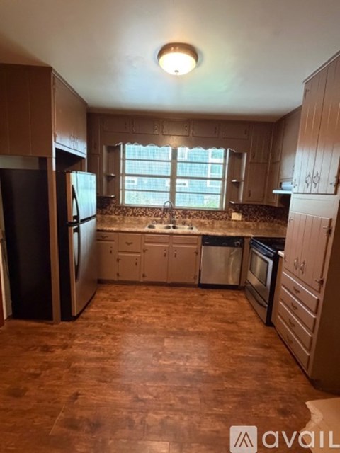 A kitchen with wooden cabinets and a black refrigerator.