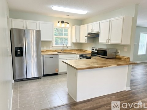 A kitchen with white cabinets and a wooden countertop.