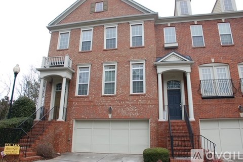 A two-story brick house with a garage and a balcony on the second floor.