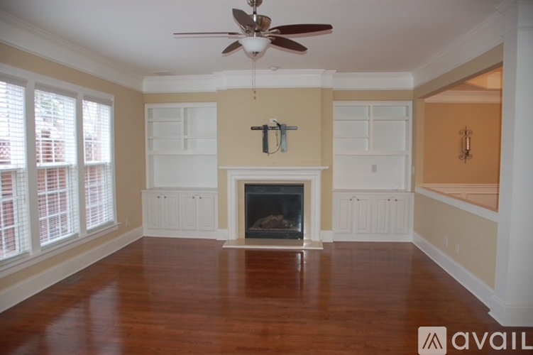 A living room with a fireplace and a ceiling fan.