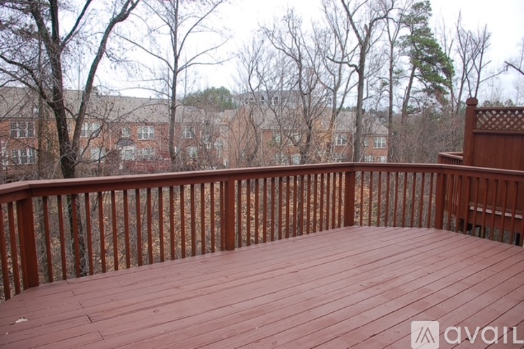 A wooden deck with a railing and trees in the background.