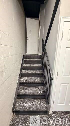 A staircase with a black railing and a white door at the top.