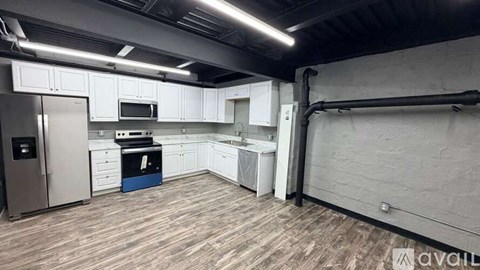 A kitchen with white cabinets and a wooden floor.
