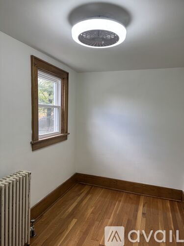 A room with a window, wooden floor, and a radiator.