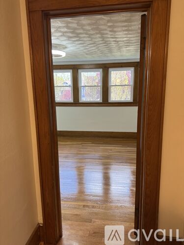 A room with a wooden floor and a window with a view of trees.