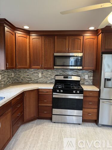 A kitchen with wooden cabinets and a stone backsplash.