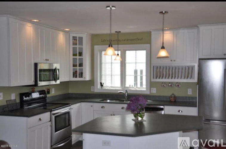 A kitchen with white cabinets and a black countertop.