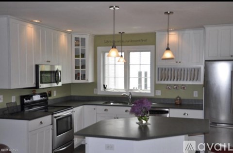 A kitchen with white cabinets and a black countertop.