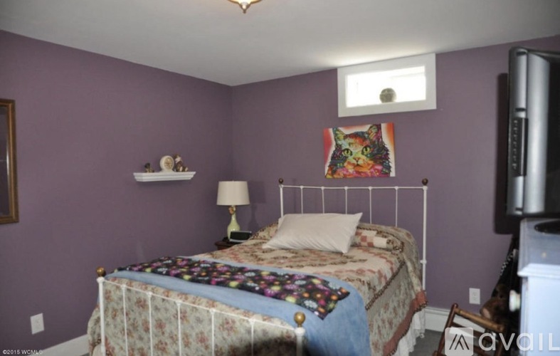 A bedroom with purple walls and a bed with a white frame.