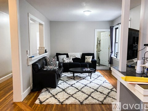 A black couch with a white pillow is in the middle of a room.