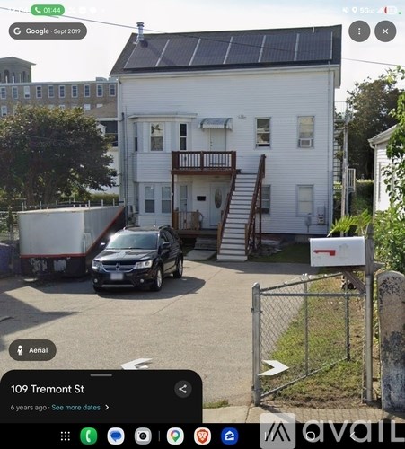 A white house with a black car parked in front.