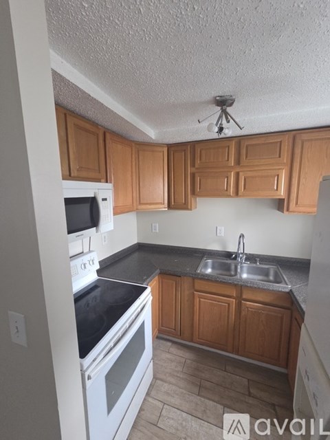 A kitchen with wooden cabinets and a black countertop.
