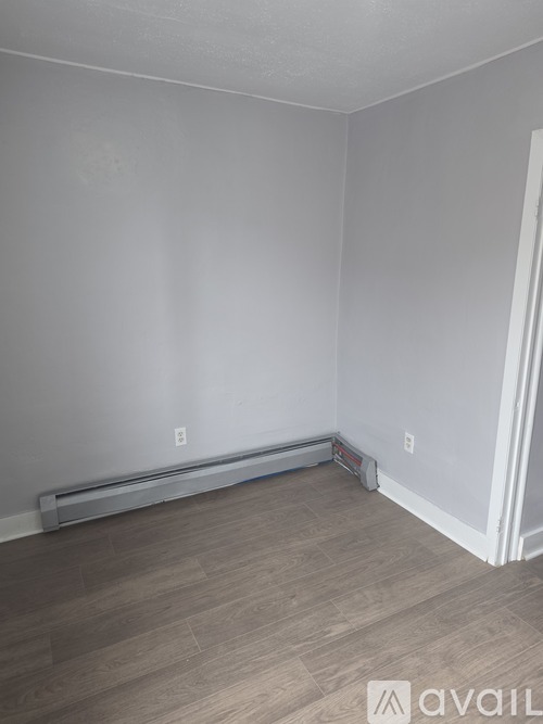 A room with a white wall and a wooden floor.