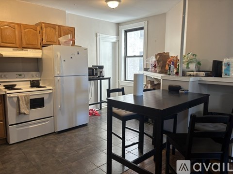 A kitchen with a white refrigerator and a black table.