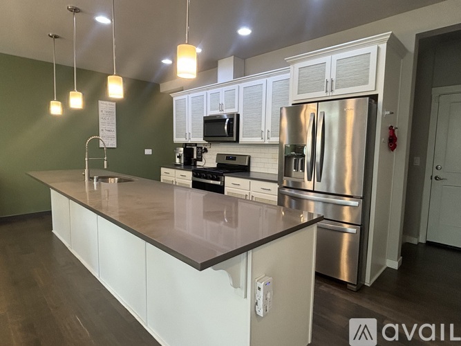 A kitchen with a stainless steel refrigerator and white cabinets.