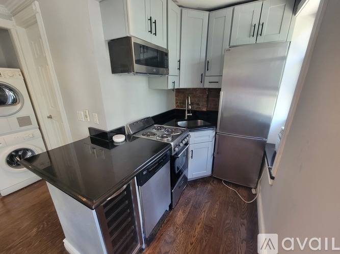 A kitchen with a black countertop and stainless steel appliances.