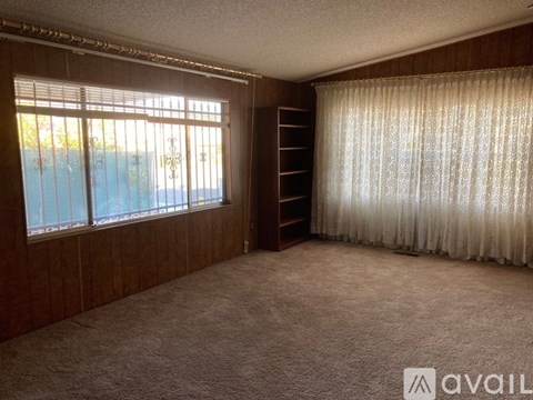 A room with a window, curtains, and a carpeted floor.