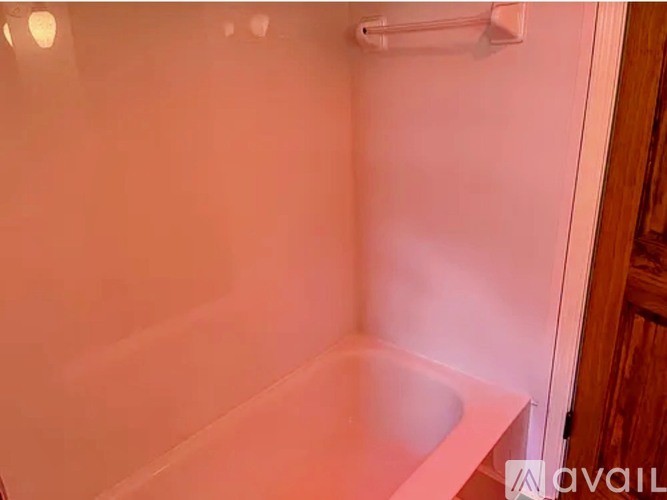 A white bathtub in a bathroom with a shower head above it.