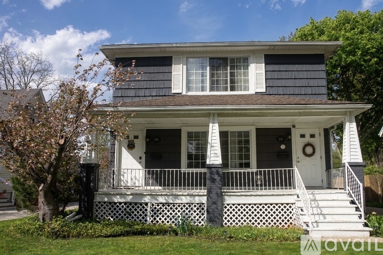 A two-story house with a white front porch and black roof.