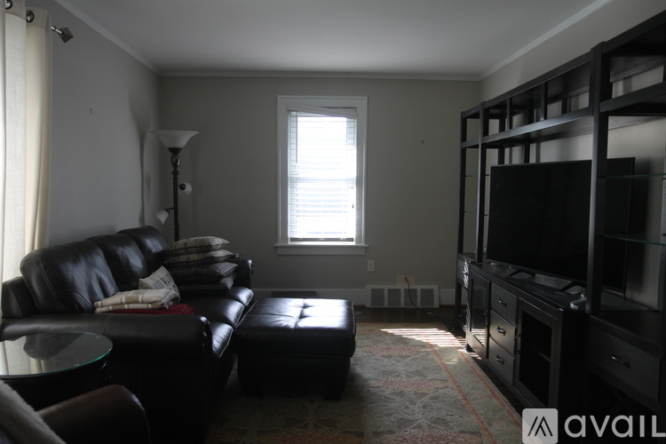 A living room with a black leather couch and a television.