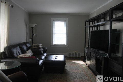 A living room with a black leather couch and a television.