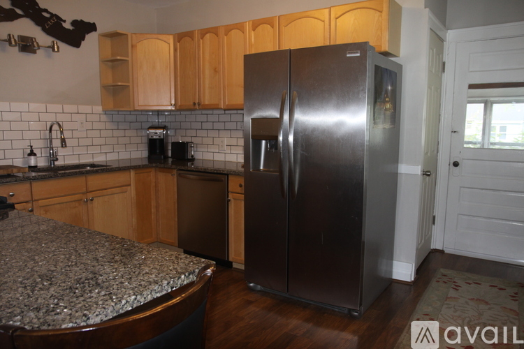 A kitchen with a granite counter top and a stainless steel refrigerator.