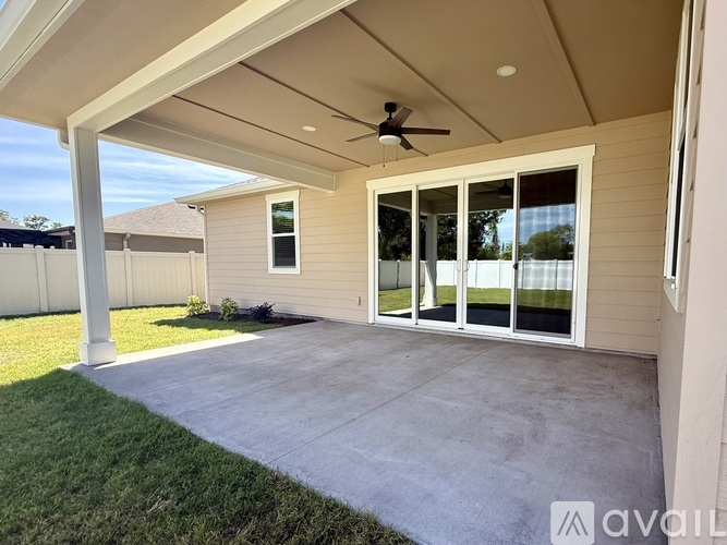 A patio with a ceiling fan and sliding glass doors.