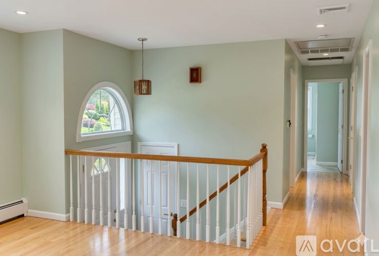 A room with a wooden floor and a white railing.