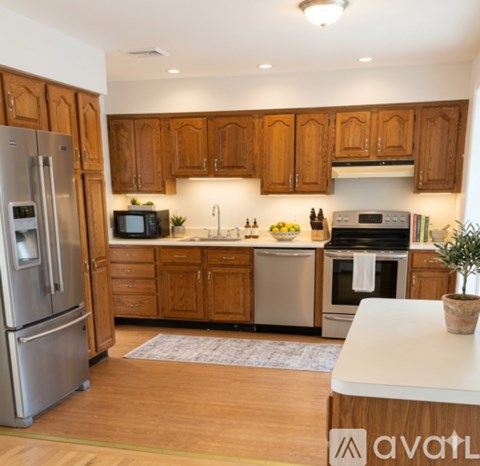A kitchen with wooden cabinets and a refrigerator on the left.