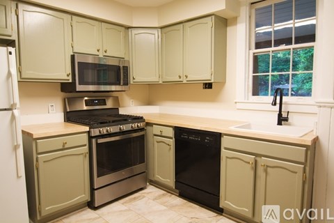 A kitchen with green cabinets and a black stove top oven.