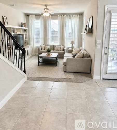 A living room with a staircase on the left and a couch set in the middle.