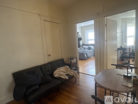 A living room with a black couch and a wooden table.