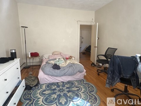 A bedroom with a bed, chair, and a rug.