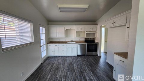A kitchen with white cabinets and a wooden floor.