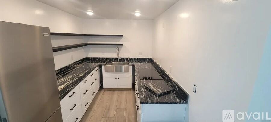 A kitchen with a refrigerator, sink, and countertops.